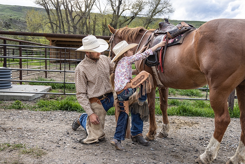 Father's day image helping little girl on horse.
